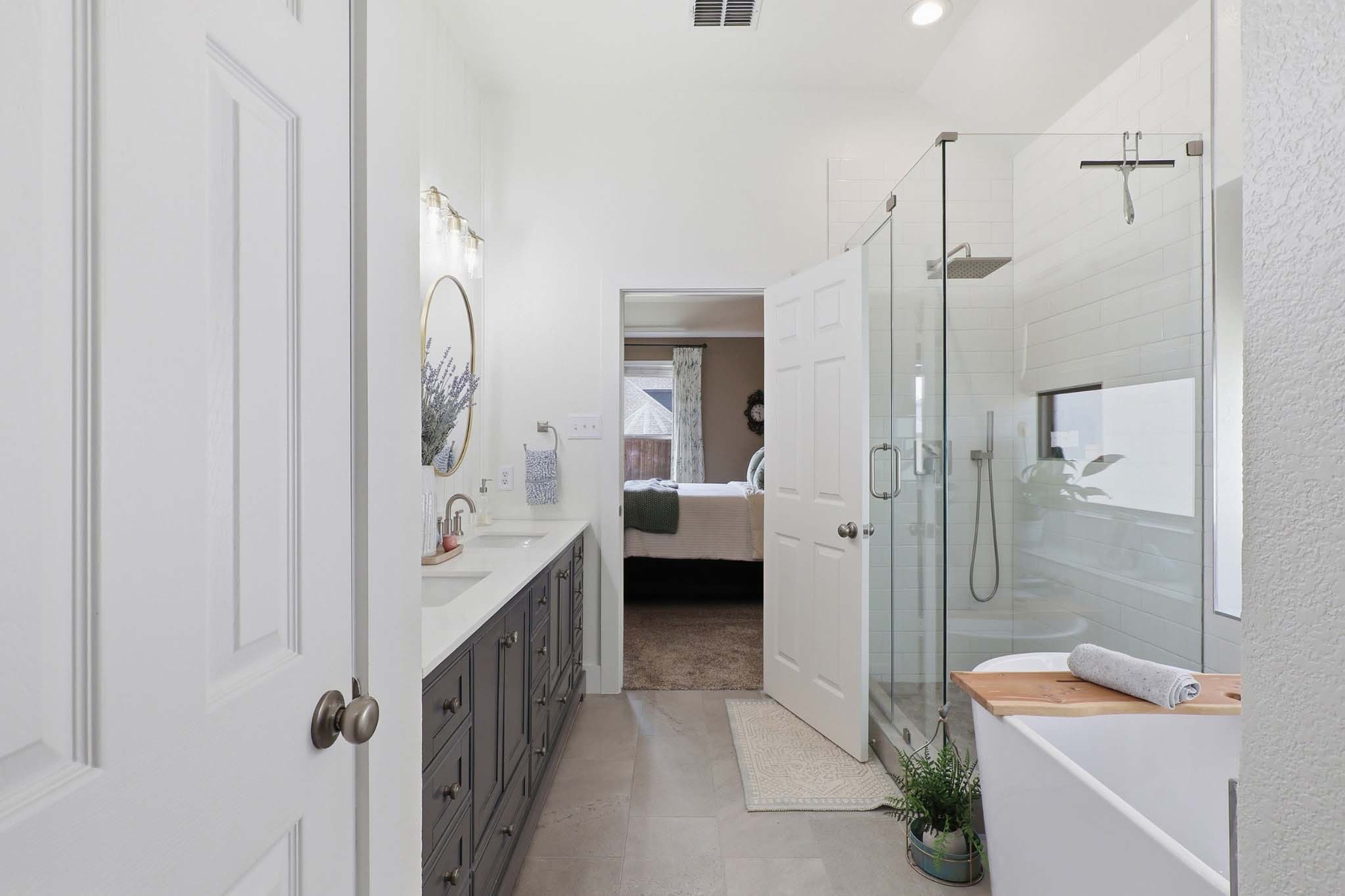Master bathroom remodel with gray double vanity, glass walk-in shower, and freestanding tub