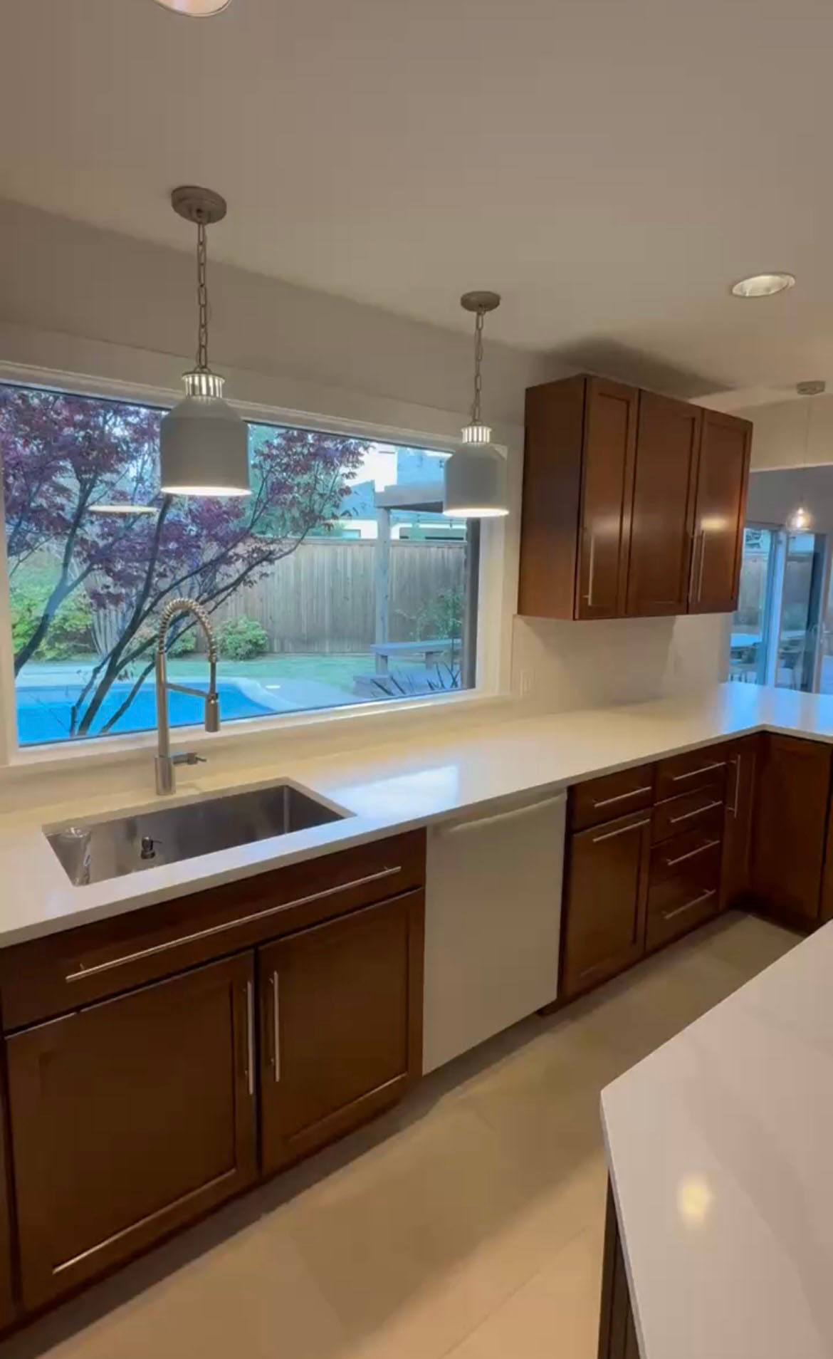 Kitchen remodel with wood cabinets, white quartz countertops, and large window over sink