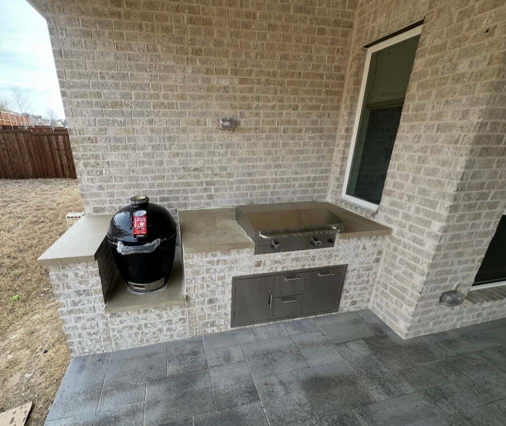 Custom outdoor kitchen with built-in grill, kamado smoker, and brick surround